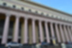 Manila grand post office building with pink columns, prominent "POST OFFICE BUILDING" text. Cars parked in front on a clear day.