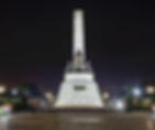 A white marble monument with the sculpture of Jose Rizal lighted in the dark night skies.