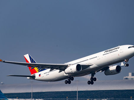 Philippine Airlines jet labeled Philippines lifts off above airport terminal under clear blue sky.