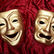 Two gold theater masks, one smiling and one frowning, on red velvet fabric, symbolizing comedy and tragedy.