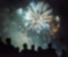 Silhouettes of people watching vibrant fireworks burst against a dark night sky, creating an exciting and festive atmosphere.