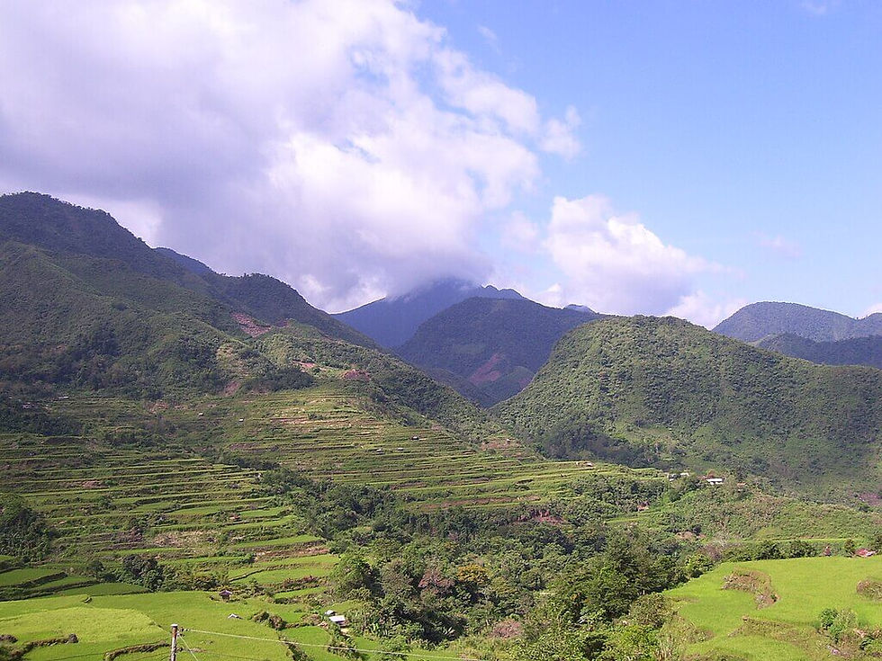 Mount Binuluan a Lush green terraced hills and mountains under a partly cloudy blue sky, creating a serene and vibrant landscape.