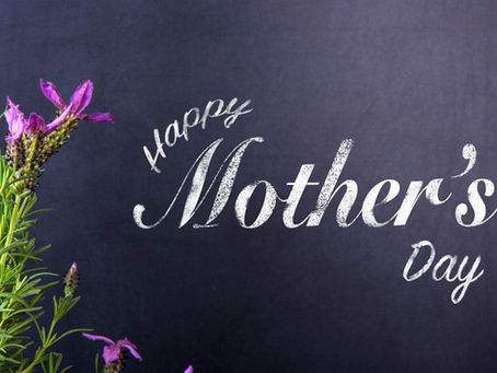 Purple wildflowers on the left, dark background. White text reads "Happy Mother's Day." Elegant and celebratory mood.