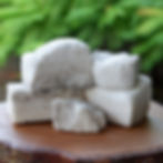 Blocks of white Tultul Salt from Guimaras stacked on a wooden surface, with a lush green background, creating a natural and clean aesthetic.
