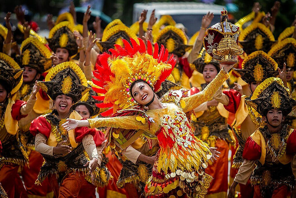 Sinulog Festival Dancers in ornate, colorful costumes with feathered headdresses celebrate joyfully. Vibrant reds and yellows dominate the festive scene.