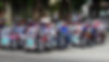 A bunch of colorful tricycle line up on the street.