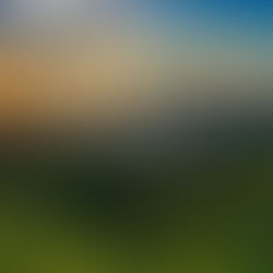 Golden sunset over a tropical bay with islands, dark green hills, and dramatic clouds above calm water.