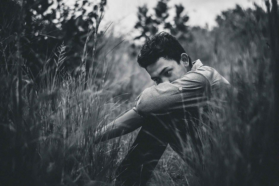 monochrome photo of man sitting on grass