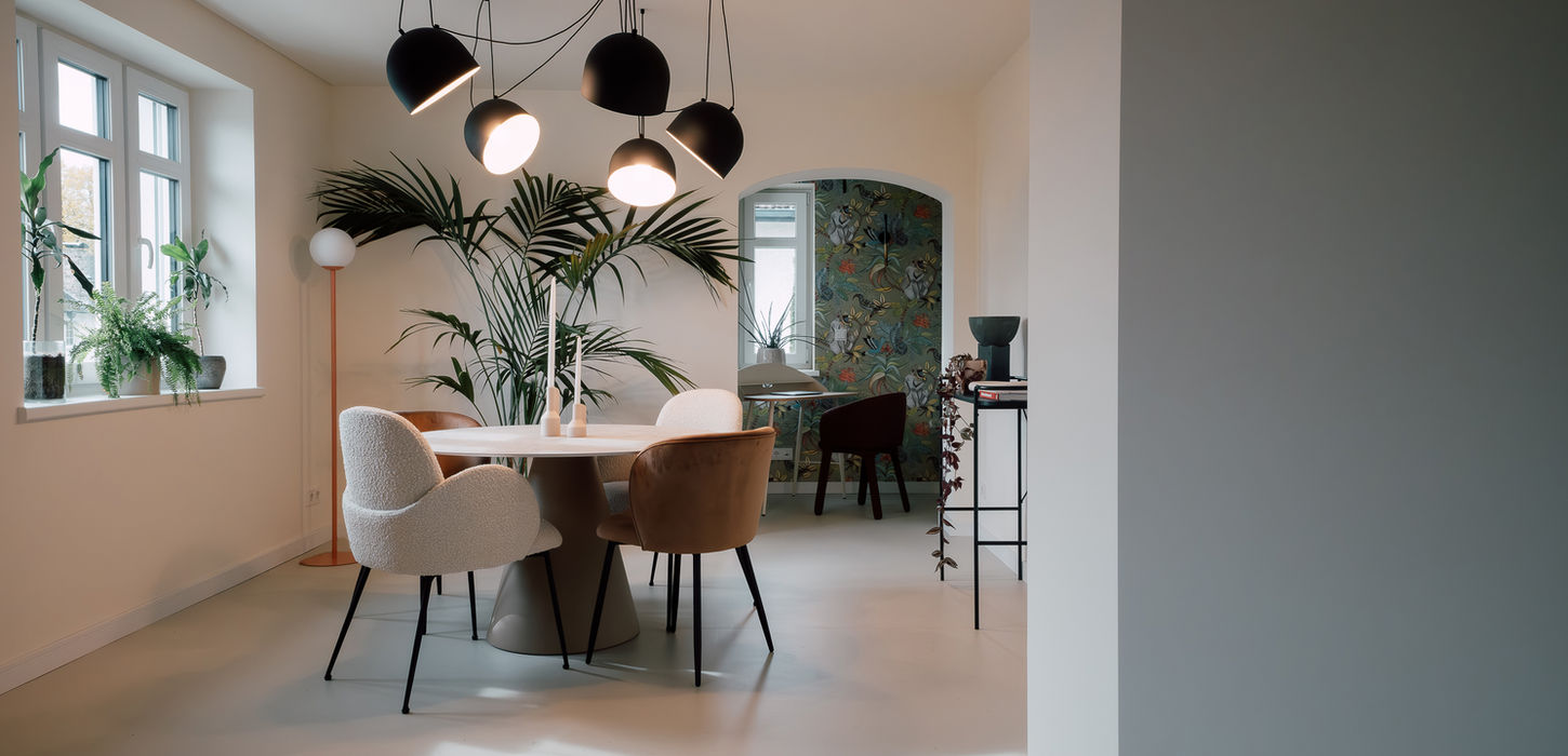 Gemütliches und schöner Wohnzimmeresstisch mit tollen Lichtspots und grüner Palme im Hintergrund