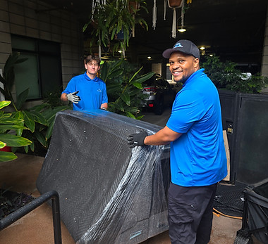 Picture of two smiling proffesional movers moving an office couch in San Diego