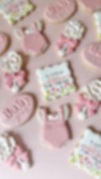 Baby shower sugar cookies with floral onesies, bows, and custom baby name plaques