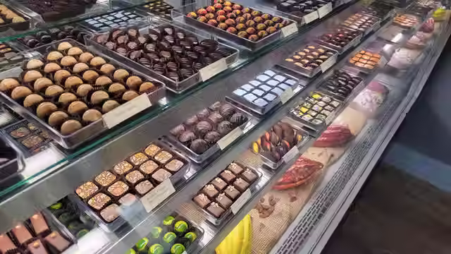 Expansive glass display case at St. Croix Chocolate Company filled with dozens of colorful, handcrafted chocolates and bonbons in flavors like Apricot Almond, Pear Caramel, St. Croix Creamy, and more, beautifully arranged in the well-kept shop.