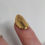 Thumbnail: gold plated silver nail on finger with a white background
