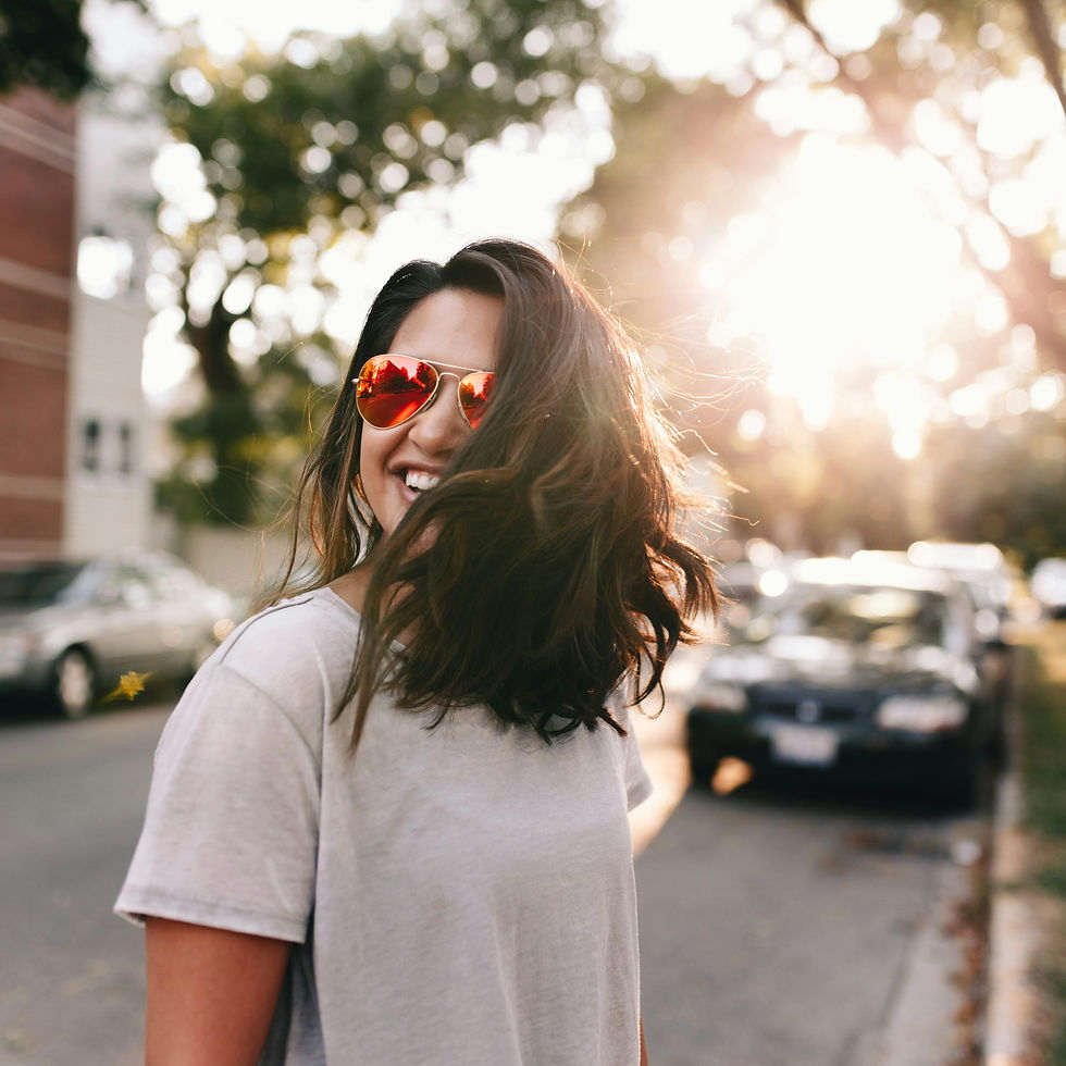 Photo of a woman smiling, outside on the street.