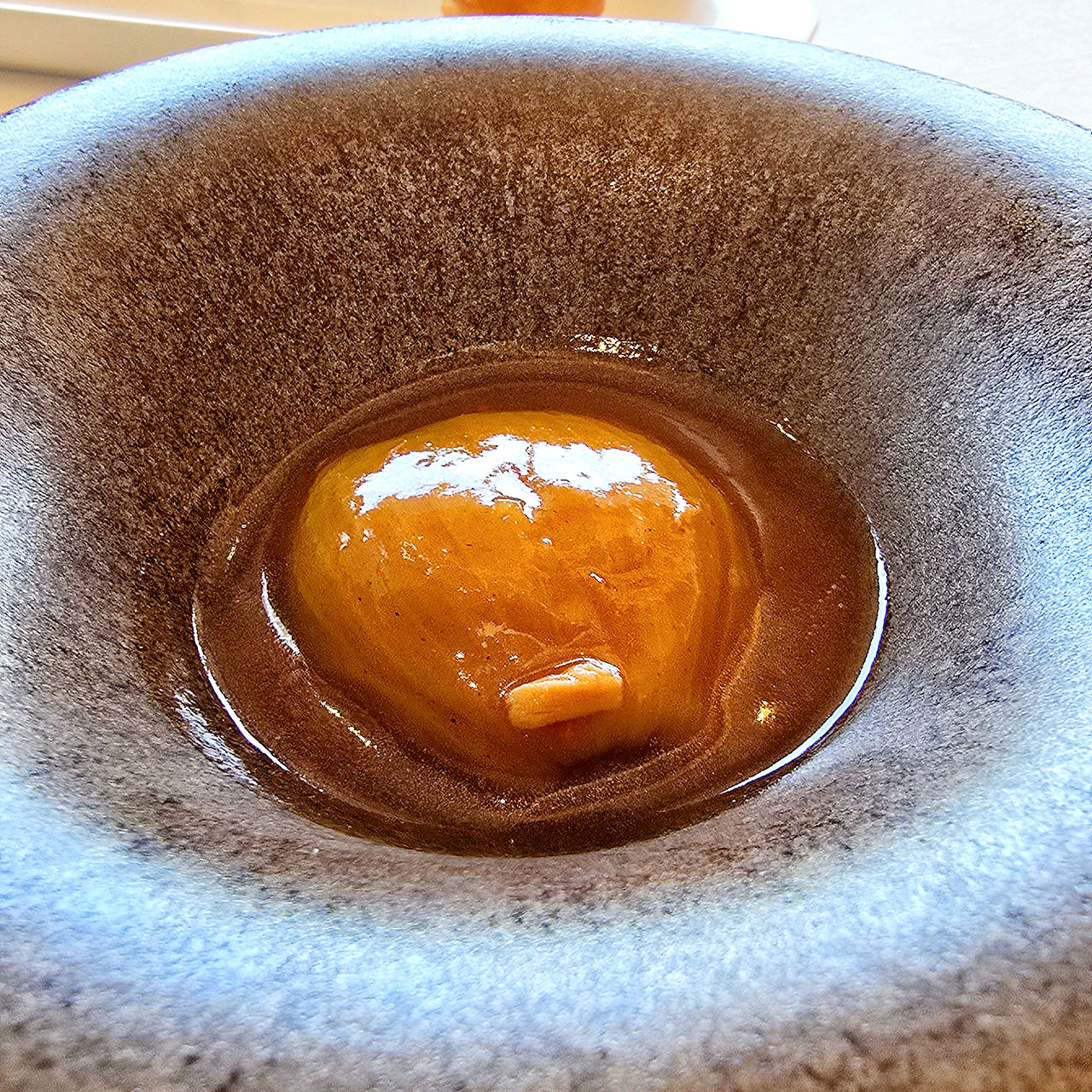 Onion stuffed with stewed meat, served on a dark plate.