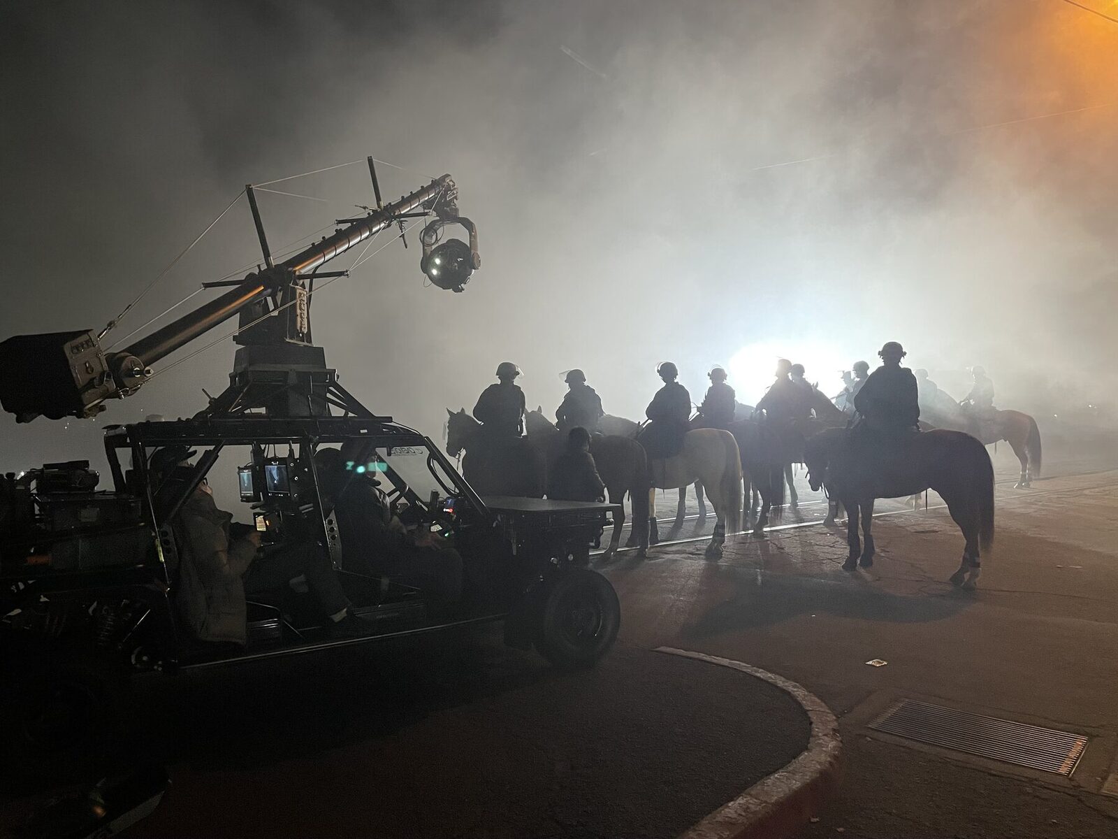 A camera car and riders on horseback in fog at night