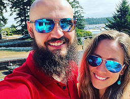 Dylan and Lexie smiling outdoors near the water with trees in the background