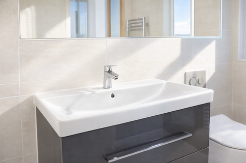Modern bathroom vanity unit with white basin, chrome mixer tap, large mirror, and neutral wall tiles.