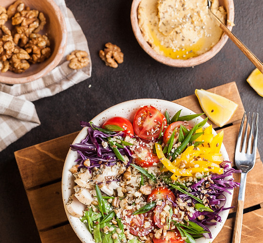 verschiedene pflanzliche Lebensmittel für eine ausgewogene Ernährung, Walnüsse, bunter Salat, Hummus