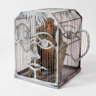 A sculpture of a macaque in a laboratory animal cage that is the shape of a human head