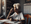 Older woman using a COPD inhaler at her kitchen table, with a wall calendar behind her