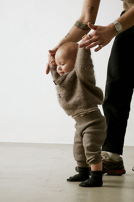 young baby boy learning to walk with dad's help