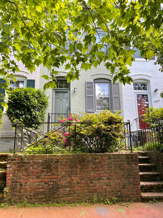 The sidewalk view with brick retaining wall, steps and black metal fencing, (D. Vogt, May 2022)