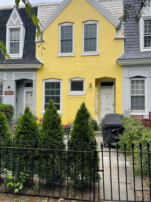 The sidewalk view with black metal fence, recessed front entry and square pavers in front patio area - 806 New Hampshire Ave