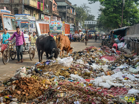 Overflowing landfill with a city skyline in the background, juxtaposing urban growth and waste mismanagement in India.