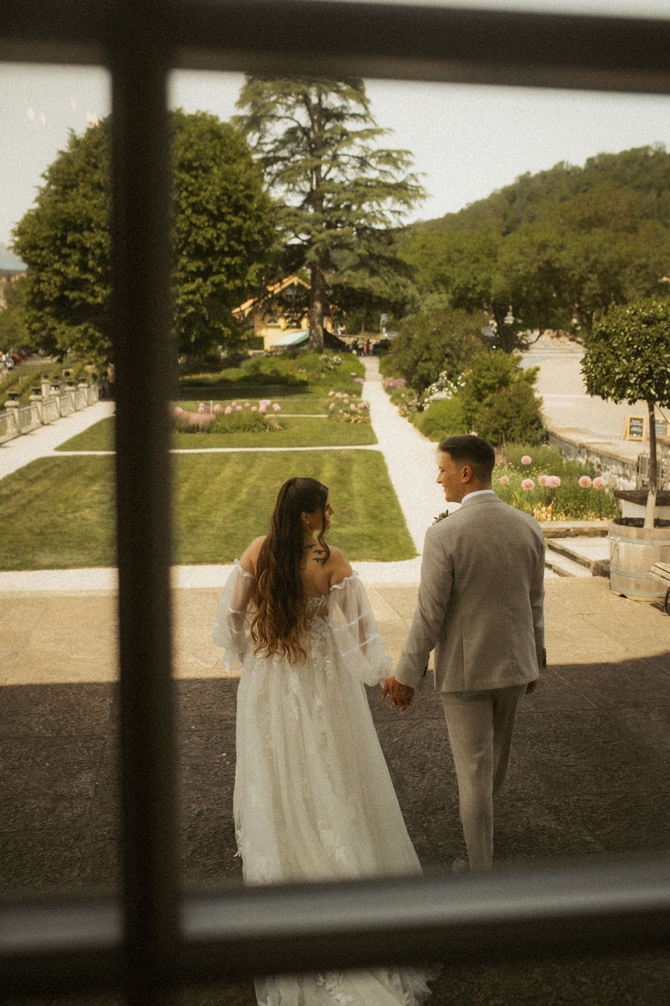 Brautpaar steht vor einem alten Fenster beim Schlossgarten Spiez
