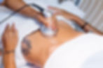 Procedimento estético de ultrassom corporal sendo realizado na região abdominal de uma paciente, com aplicação de gel condutor e equipamento específico.