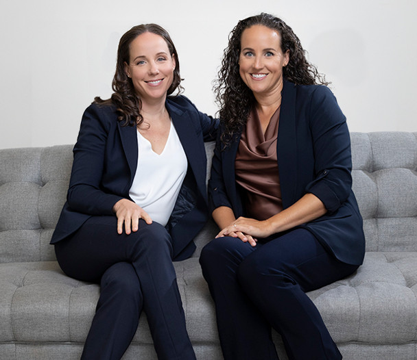 Two Realtors Sitting on a Grey Couch Ready to Provide Excellent Service