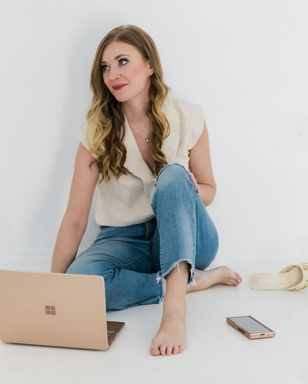 Woman seated on the floor with a laptop nearby in a calm, neutral space_