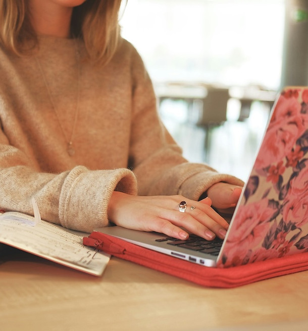 woman in beige sweater typing on laptop