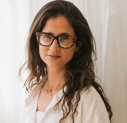 אישה צעירה עם משקפיים מחייכת למצלמה, לבושה בחולצה לבנה, neshimot