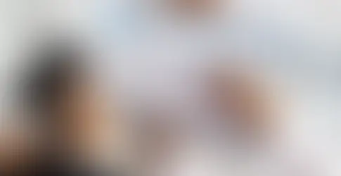 Mãos em mesa de escritório segurando canetas e documento com gráficos.