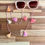 Thumbnail: Stylish 'Pink and Peaches Tassels' eyeglass chain with vibrant pink and peach beads and tassels, draped over beige sunglasses