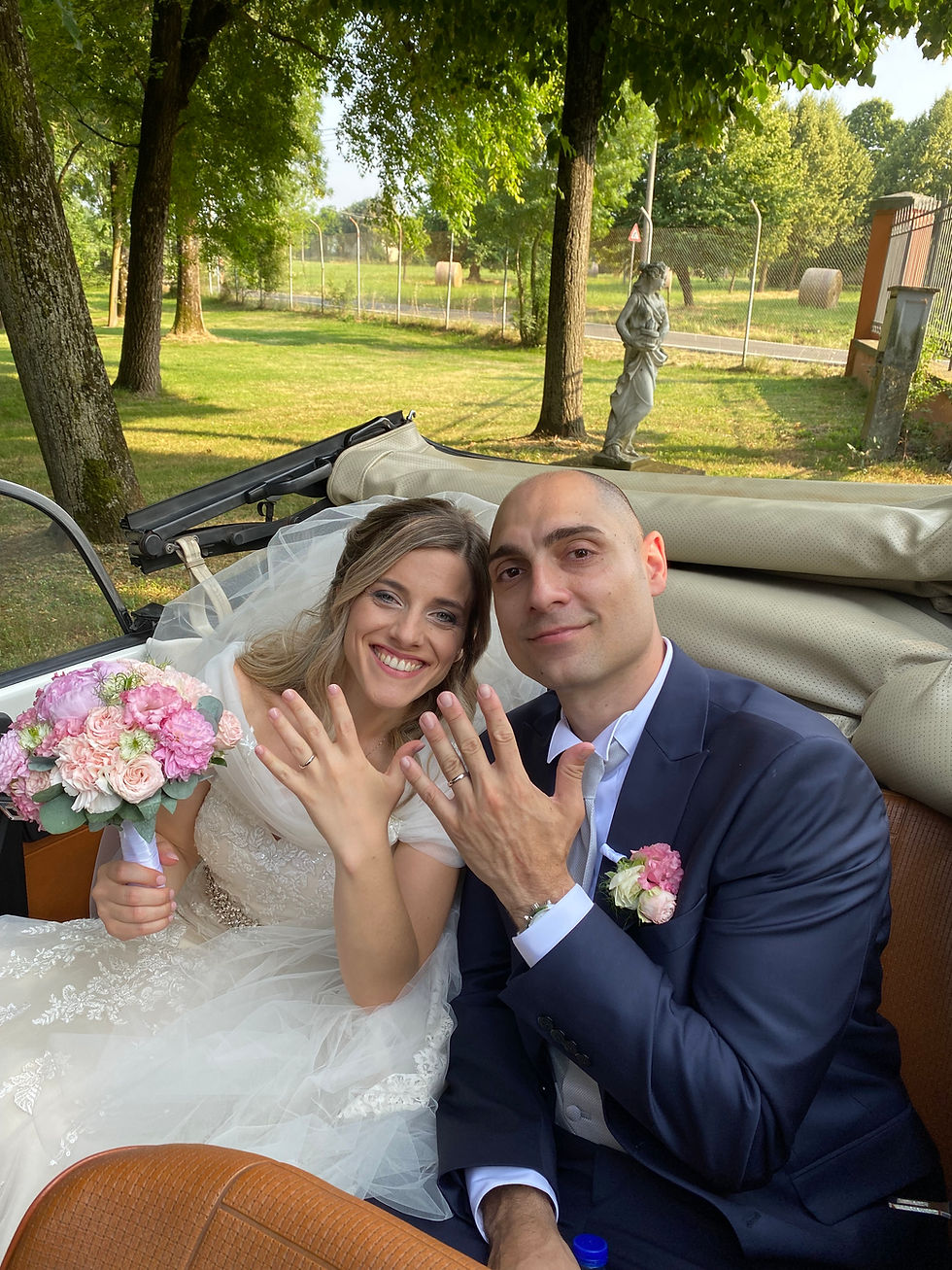 Una coppia di sposa che mostra la fede su maggiolone cabrio bianco a reggio emilia