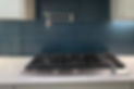 Gas cooktop in front of a dark blue tile backsplash. A pot filler is above the cooktop