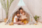 mom and her two daughters reading together in a small tent