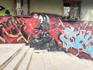 Graffiti mural of Darth Vader holding a small cat, set against a cosmic red background and flanked by colorful lettering on a Beyoğlu wall.