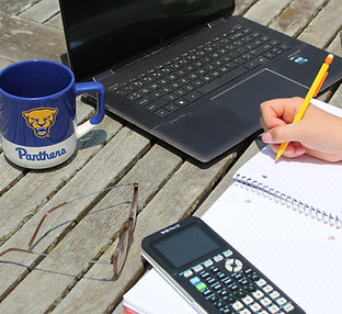 Campus Colors custom wraparound screen print mug on table with student doing homework