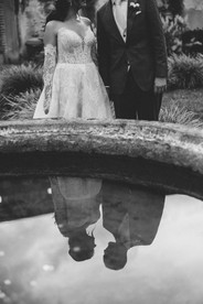 Santa Clara Ruins Gardens, a venue for luxury destination weddings in Guatemala. Bride and groom's portrait of a romantic reflection in the water of the Ruin's fountain.
