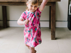 Toddler girl in a pink dress walking proudly in her new pink, sparkly sandals