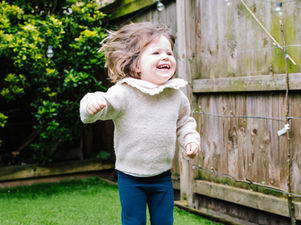 Toddler girl jumping up and down in a pair of Froddo barefoot trainers with a big smile on her face