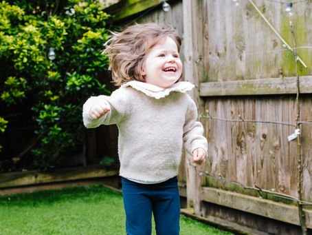 Toddler girl jumping up and down in a pair of Froddo barefoot trainers with a big smile on her face