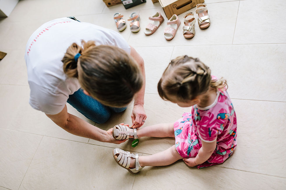 Toddler girl having a pair of gold closed toe sandals fitted