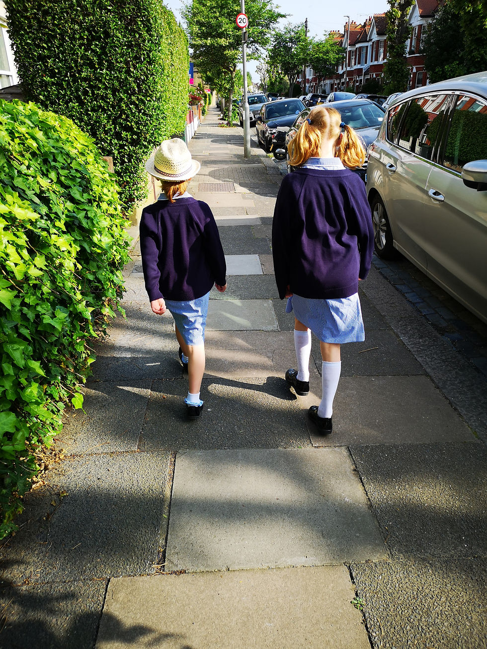 Two young girls walking to school on a sunny day