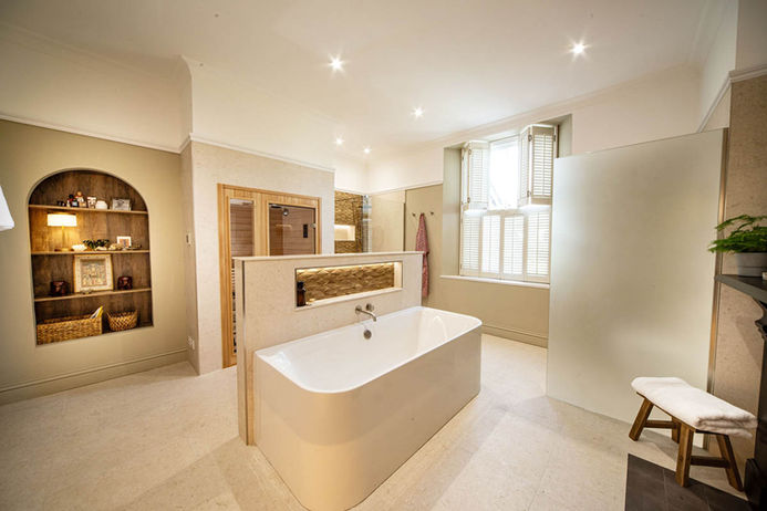Modern freestanding white bathtub in a luxury ensuite bathroom with sauna in Cardiff, South Wales.