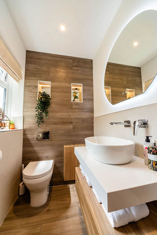 Modern round bathroom mirror with LED lighting above a grey floating vanity unit, Cardiff, South Wales.